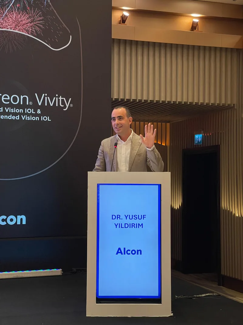 Alcon kürsüsünde konuşan Prof. Dr. Yusuf Yıldırım; arkasındaki ekranda Clareon Vivity sunumu.