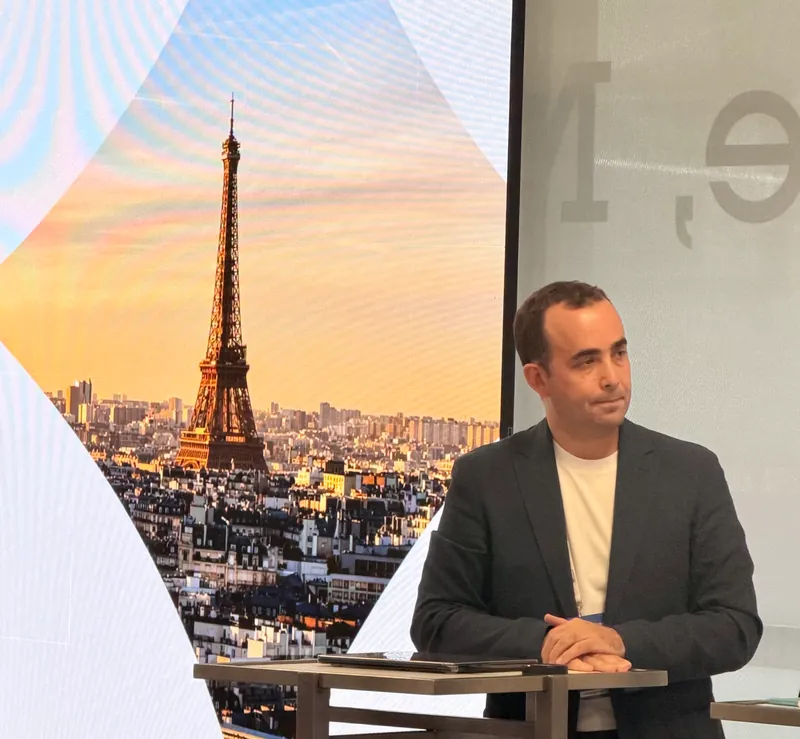 Paris toplantısında sahnede konuşmacılar; arkada Eyfel Kulesi görseli.